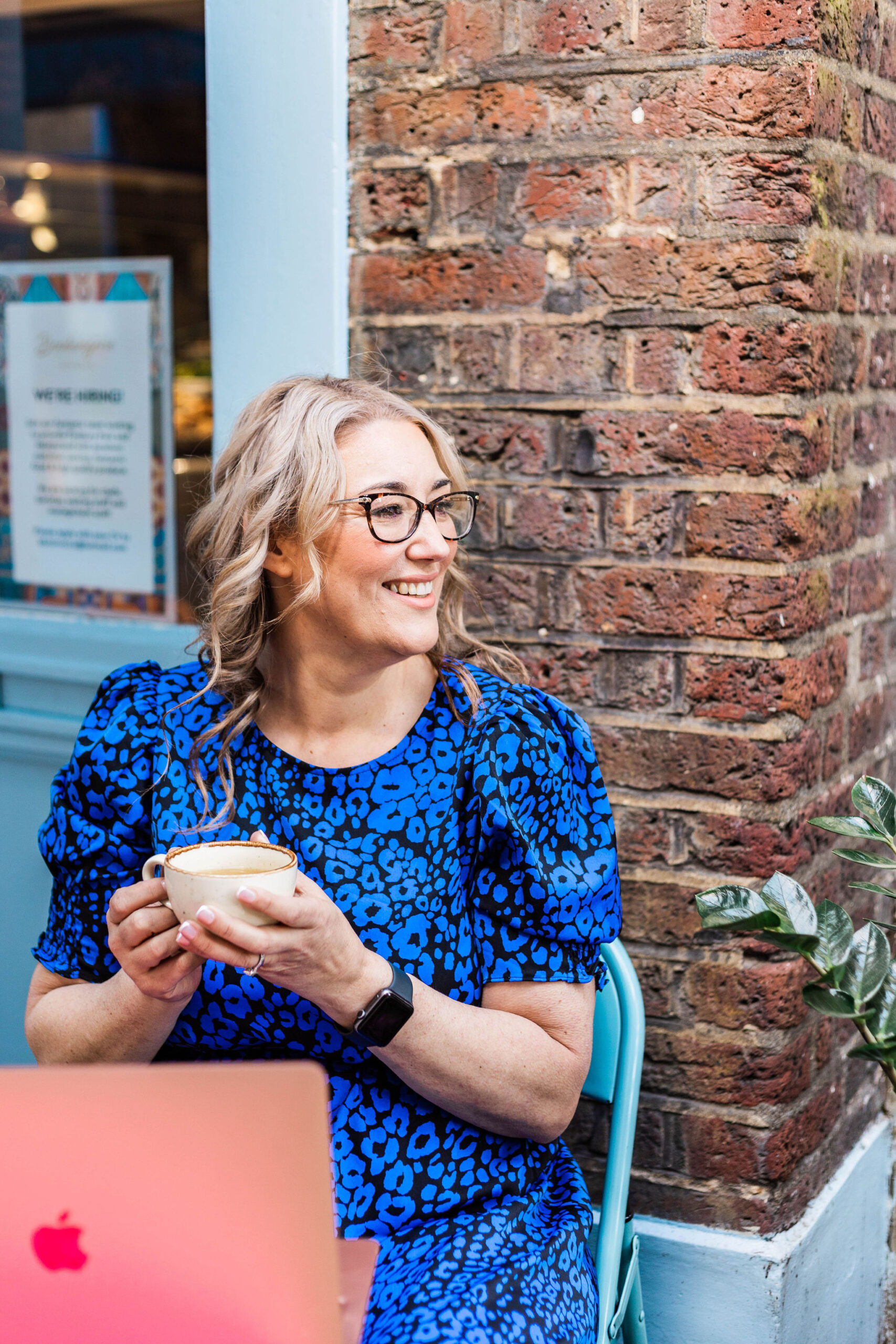 Geri holding a cup of tea at a café.